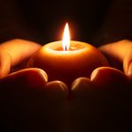 holding round lit candle